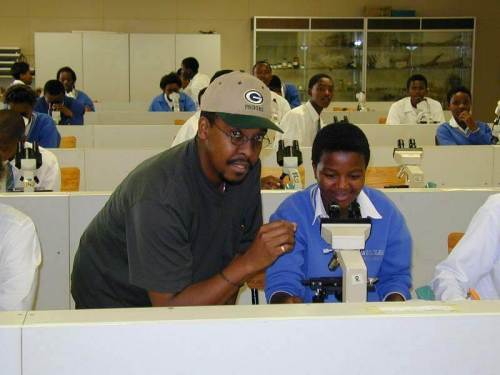 A lecturer in the Botany department showing a student from a local school how to use a light microscope.